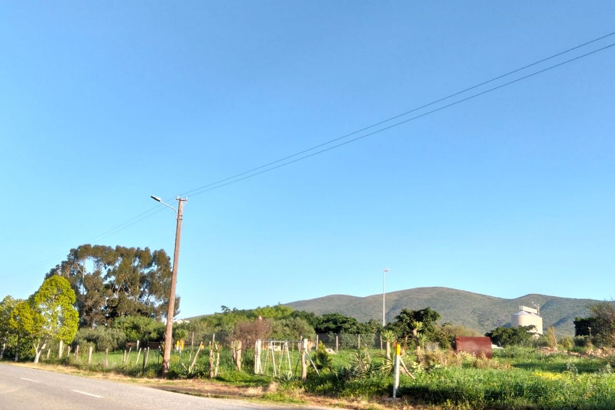 A street-level view of the vacant residential land, featuring existing wire fencing, utility infrastructure, and scenic mountain views in the background.