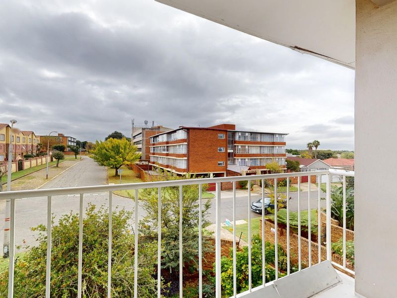 An elevated balcony with a metal balustrade offering an open view of the surrounding residential street and neighborhood.