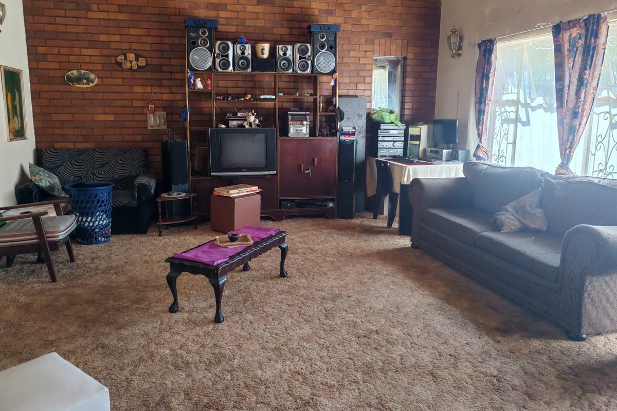 Spacious living room featuring an exposed brick feature wall, timber ceiling paneling, and large windows with security bars.