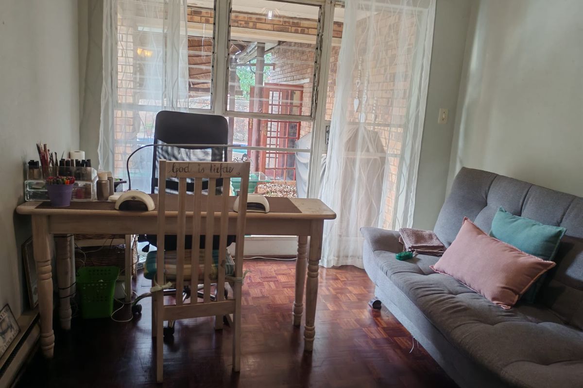A multi-purpose room featuring parquet flooring and a sliding glass door with security gate, providing access to the outdoor area.