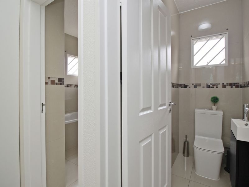 A modern, well-maintained bathroom featuring tiled walls with decorative accents, a wall-mounted vanity, and a toilet.