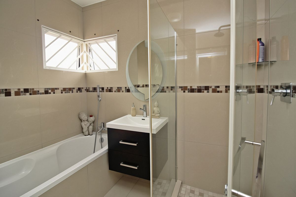 Modern bathroom featuring a built-in bathtub, a separate glass-enclosed shower, and a sleek wall-mounted vanity with tiled finishes.