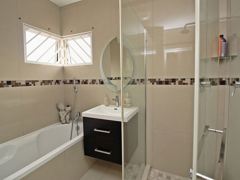 Modern bathroom featuring a built-in bathtub, a separate glass-enclosed shower, and a sleek wall-mounted vanity with tiled finishes.