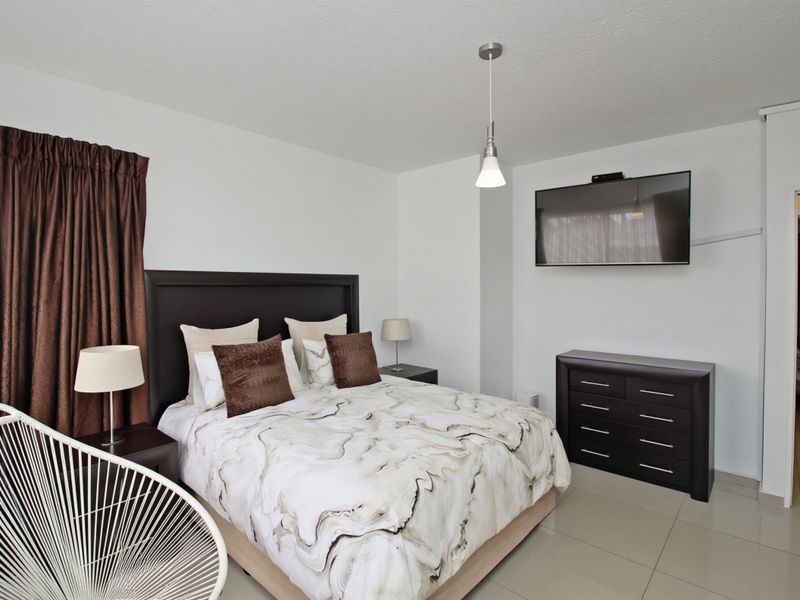 A well-maintained bedroom featuring neutral tiled flooring and a central pendant light fixture.
