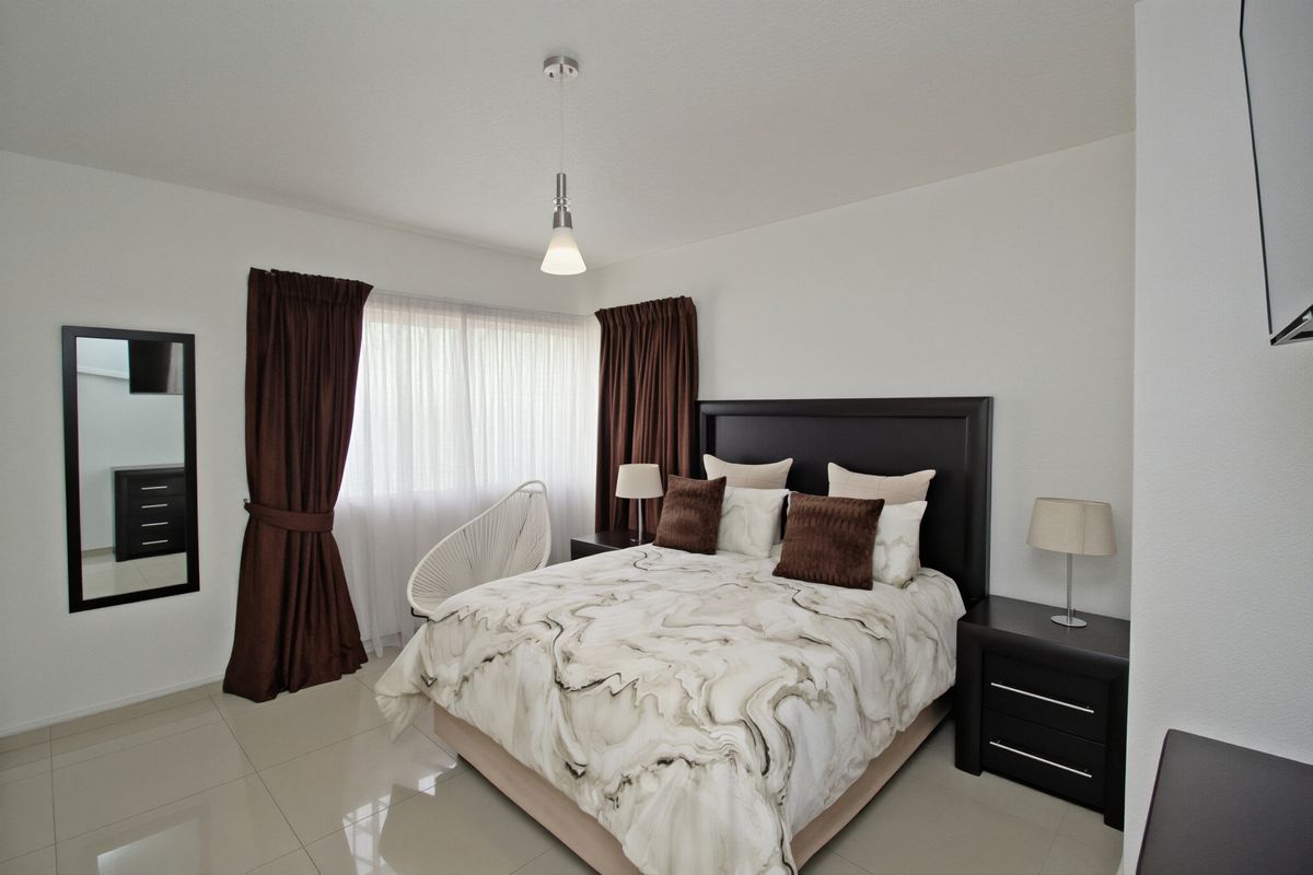 A well-maintained bedroom featuring neutral tiled flooring and modern pendant lighting, offering a clean and comfortable living space.