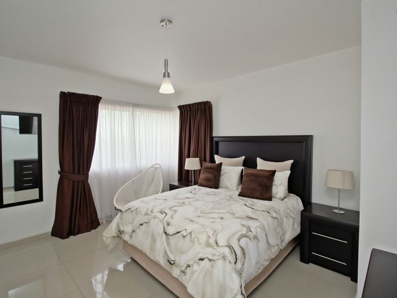 A well-maintained bedroom featuring neutral tiled flooring and modern pendant lighting, offering a clean and comfortable living space.