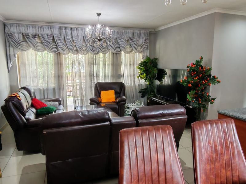Open-plan living and dining area featuring tiled flooring, decorative cornice, and a granite kitchen countertop, creating a functional and connected living space.