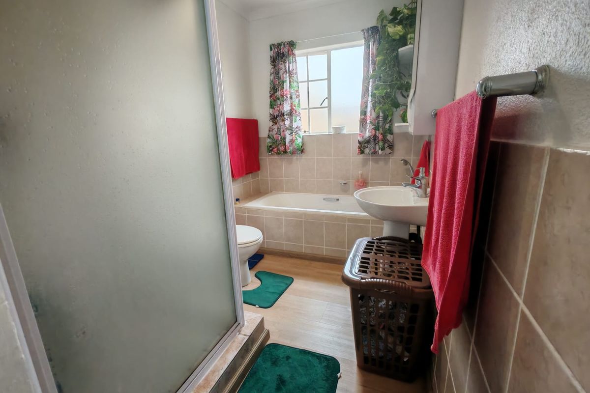 A functional bathroom featuring a bathtub, pedestal basin, and a separate shower enclosure with tiled splashbacks.