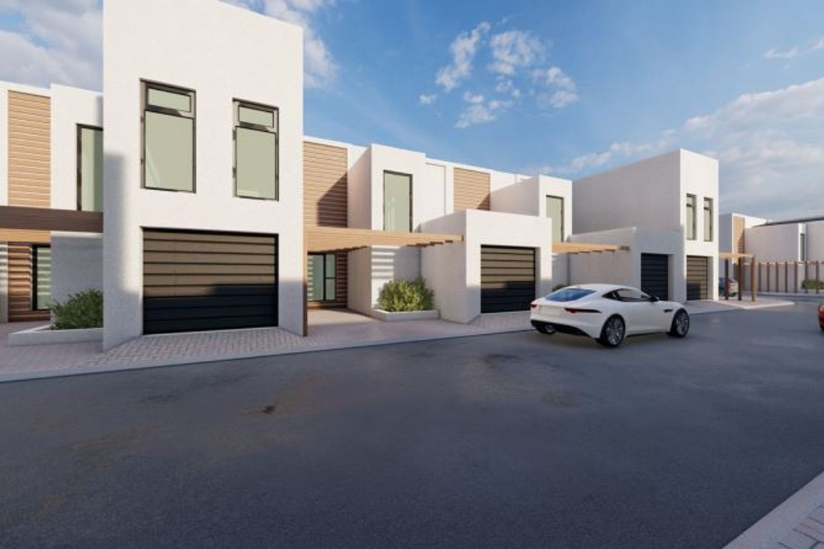 A modern residential townhouse complex featuring clean white facades, timber pergola accents, and integrated garage doors with paved driveway access.