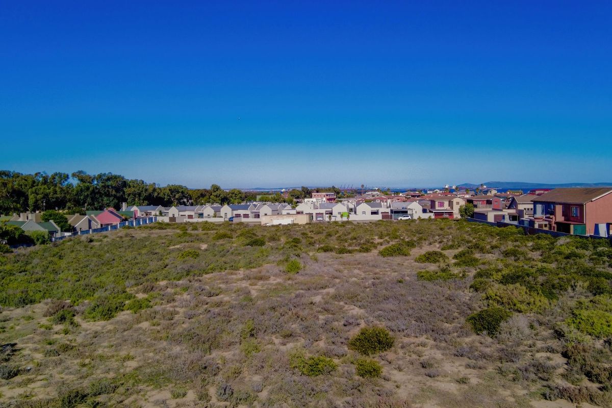 An aerial view of a large, undeveloped vacant plot of land situated in a residential neighborhood.