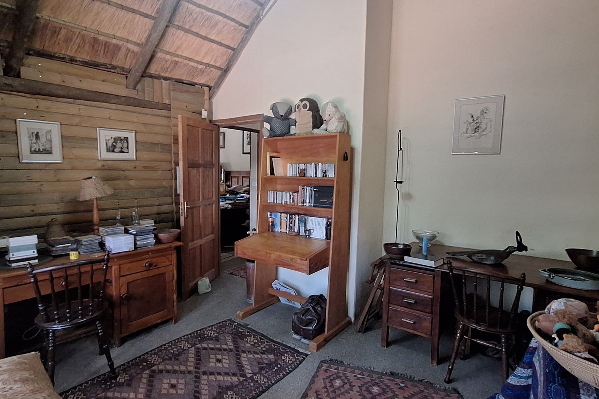 A bedroom featuring a high vaulted thatched ceiling with exposed timber rafters and rustic timber wall cladding, creating a warm, traditional atmosphere.