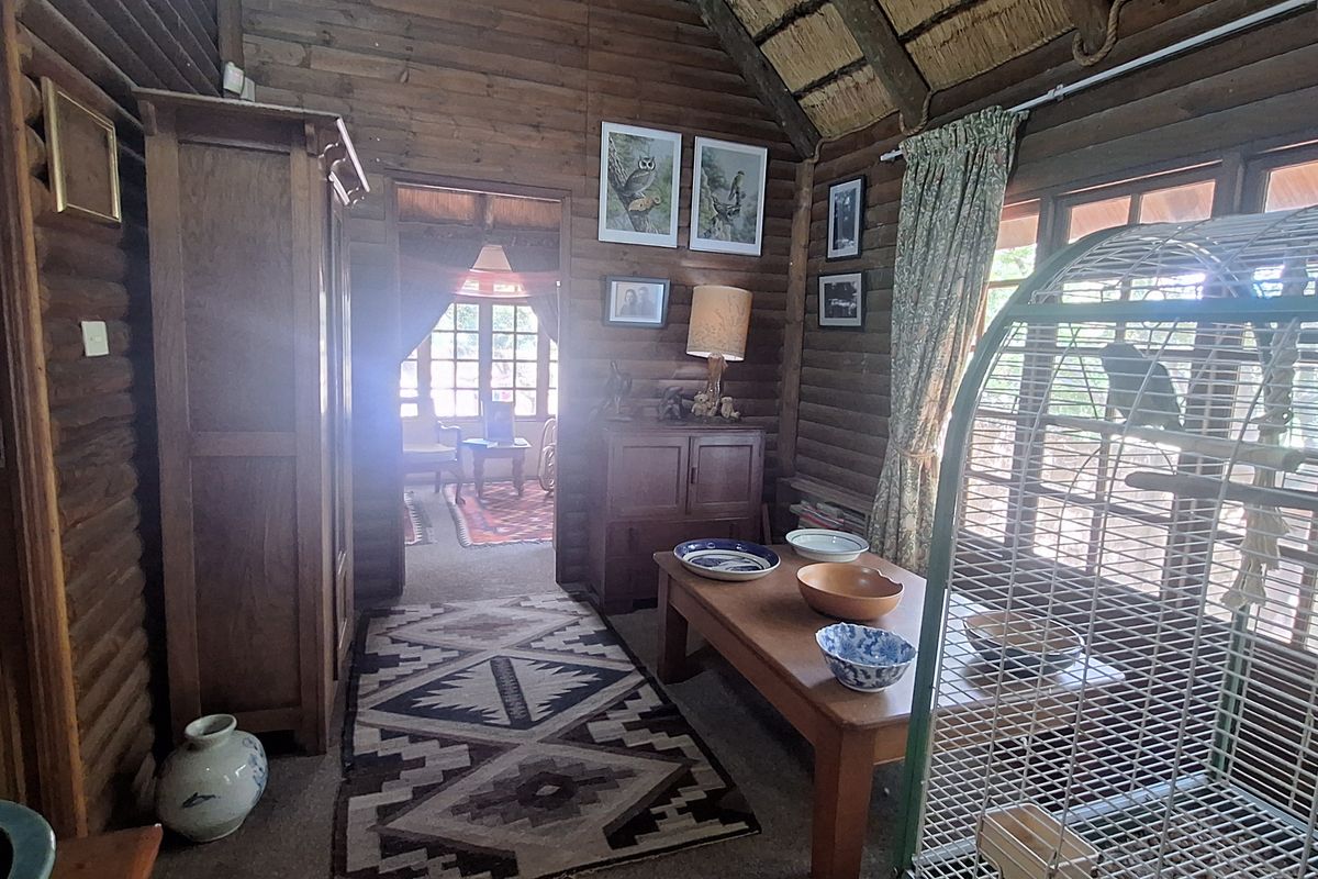 Rustic living room featuring exposed timber log walls and a vaulted thatched ceiling, creating a warm and traditional cabin-style atmosphere.