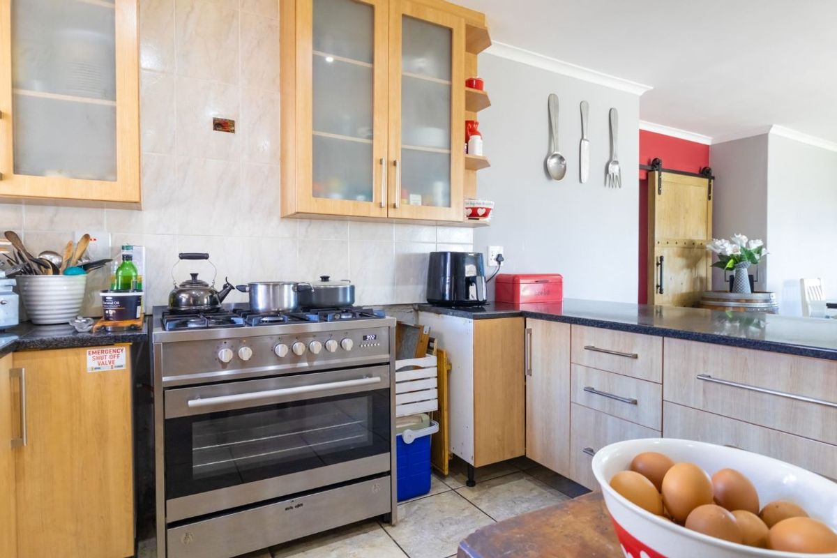 A functional kitchen featuring light wood cabinetry, granite countertops, a gas stove with oven, and a distinctive sliding barn door leading to adjacent living areas.