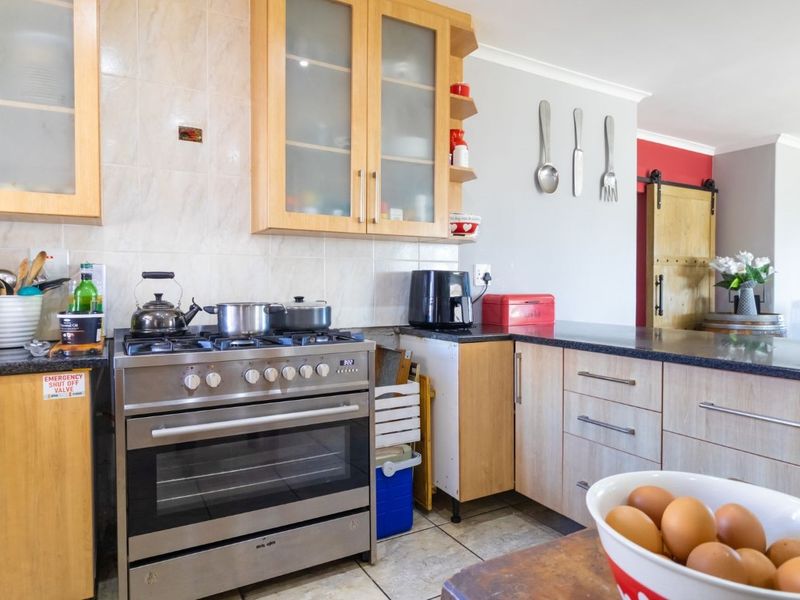 A functional kitchen featuring light wood cabinetry, granite countertops, a gas stove with oven, and a distinctive sliding barn door leading to adjacent living areas.