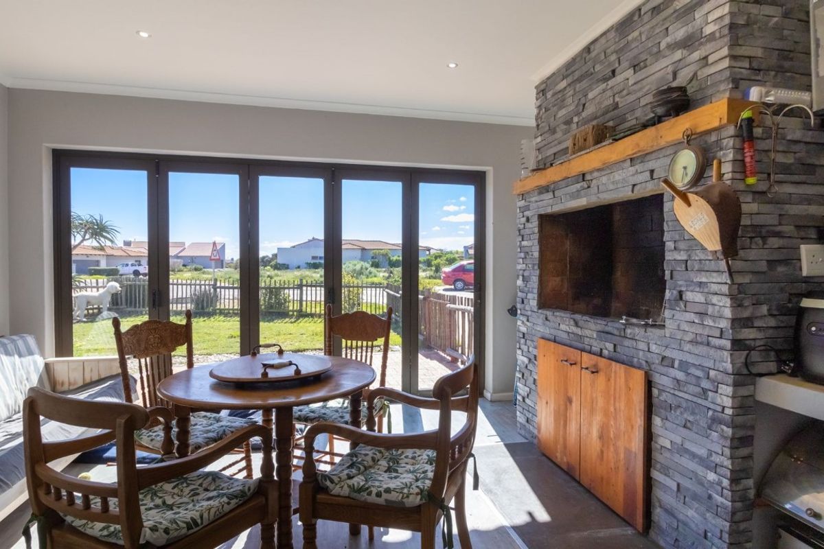 Bright living area featuring a striking stone-clad fireplace with timber mantel and large bi-fold doors opening to the garden.