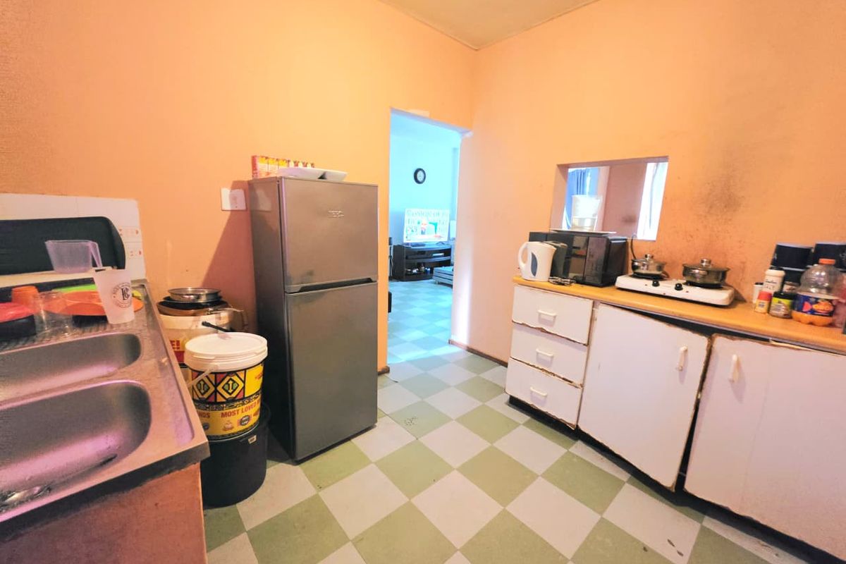 Functional kitchen featuring double bowl sink, built-in base cabinetry, and checkerboard flooring, offering potential for cosmetic updates and modernization.