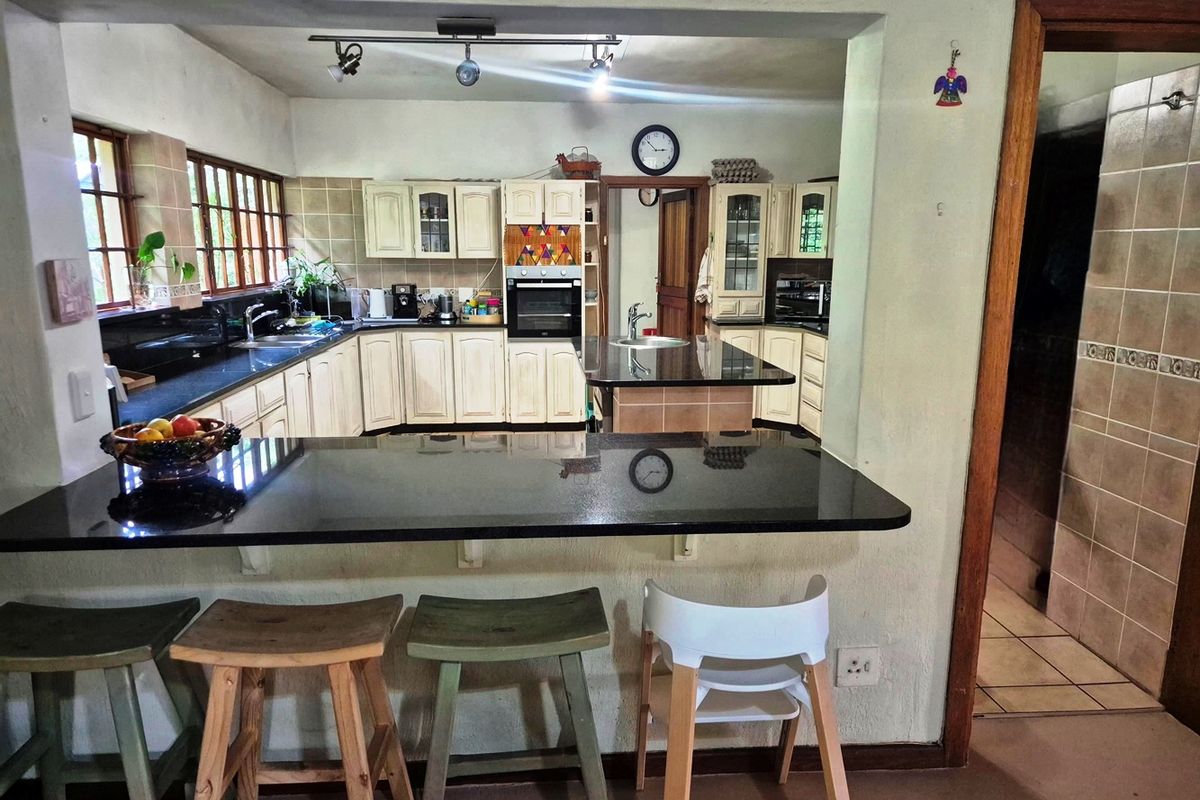A functional kitchen featuring granite countertops, a central island, built-in oven, and ample wooden cabinetry with a breakfast bar pass-through.