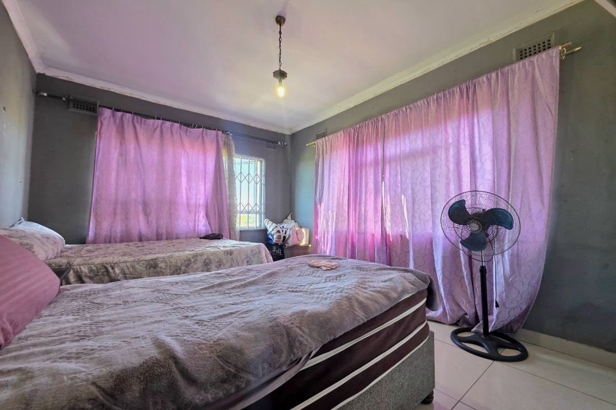 A bedroom featuring tiled flooring, security bars on the windows, and ceiling lighting, currently showing signs of wear on the wall finishes.