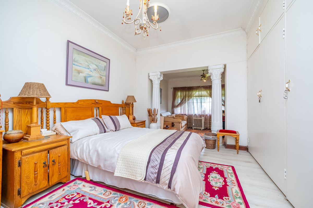 Spacious bedroom featuring decorative columns leading to an adjoining seating area, built-in wardrobes, and classic crown molding details.