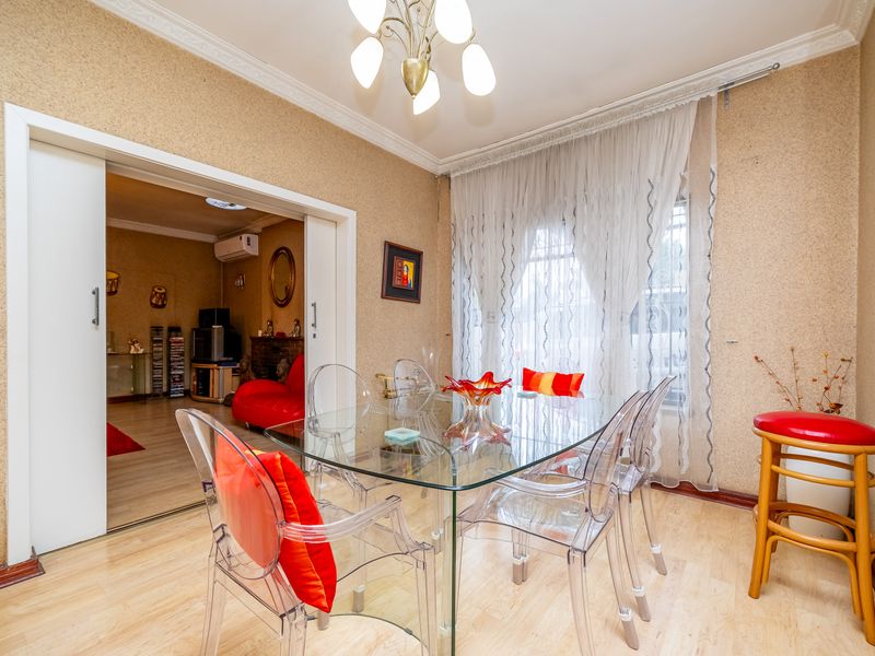 A dining room featuring light wood-look flooring, decorative crown molding, and a large sliding door opening into an adjacent living space.