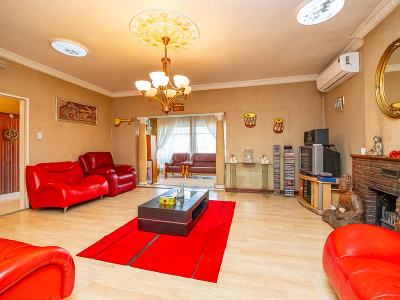 Spacious living room featuring a fireplace, decorative ceiling rose, chandelier, and split-system air conditioning unit.