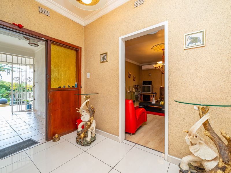 Entrance foyer featuring tiled flooring, decorative ceiling cornice, and access to the living area and covered patio through a timber-framed door.