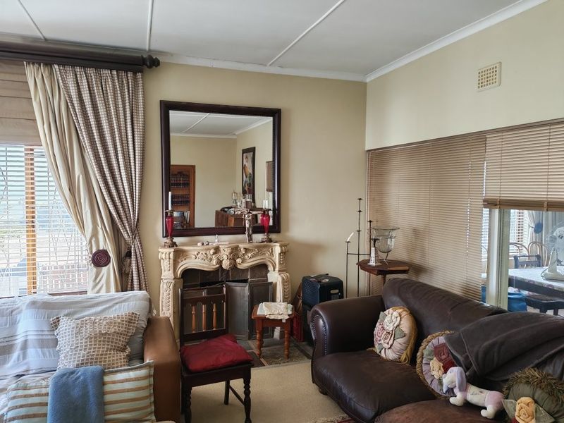 A living room featuring an ornate fireplace, neutral wall finishes, and window treatments including venetian blinds and curtains.