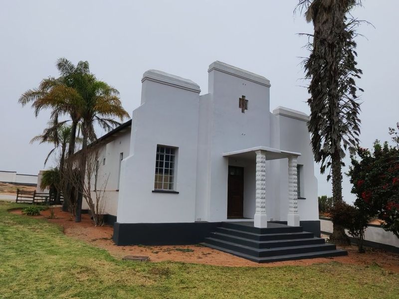 Front elevation of a small holding building featuring a covered entrance porch with decorative columns and a stepped entry.