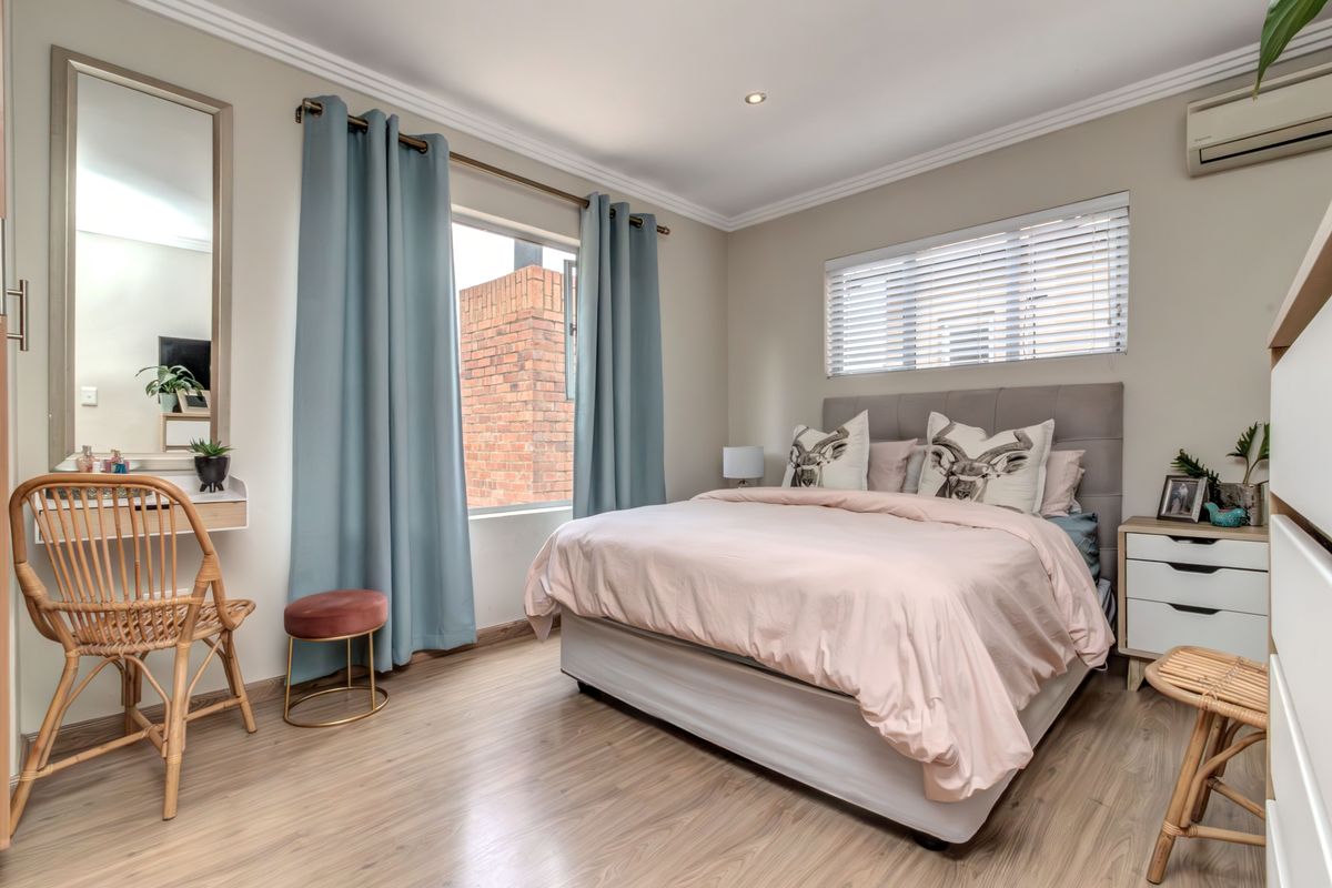 A well-maintained bedroom featuring laminate flooring, crown molding, recessed lighting, and a wall-mounted air conditioning unit.