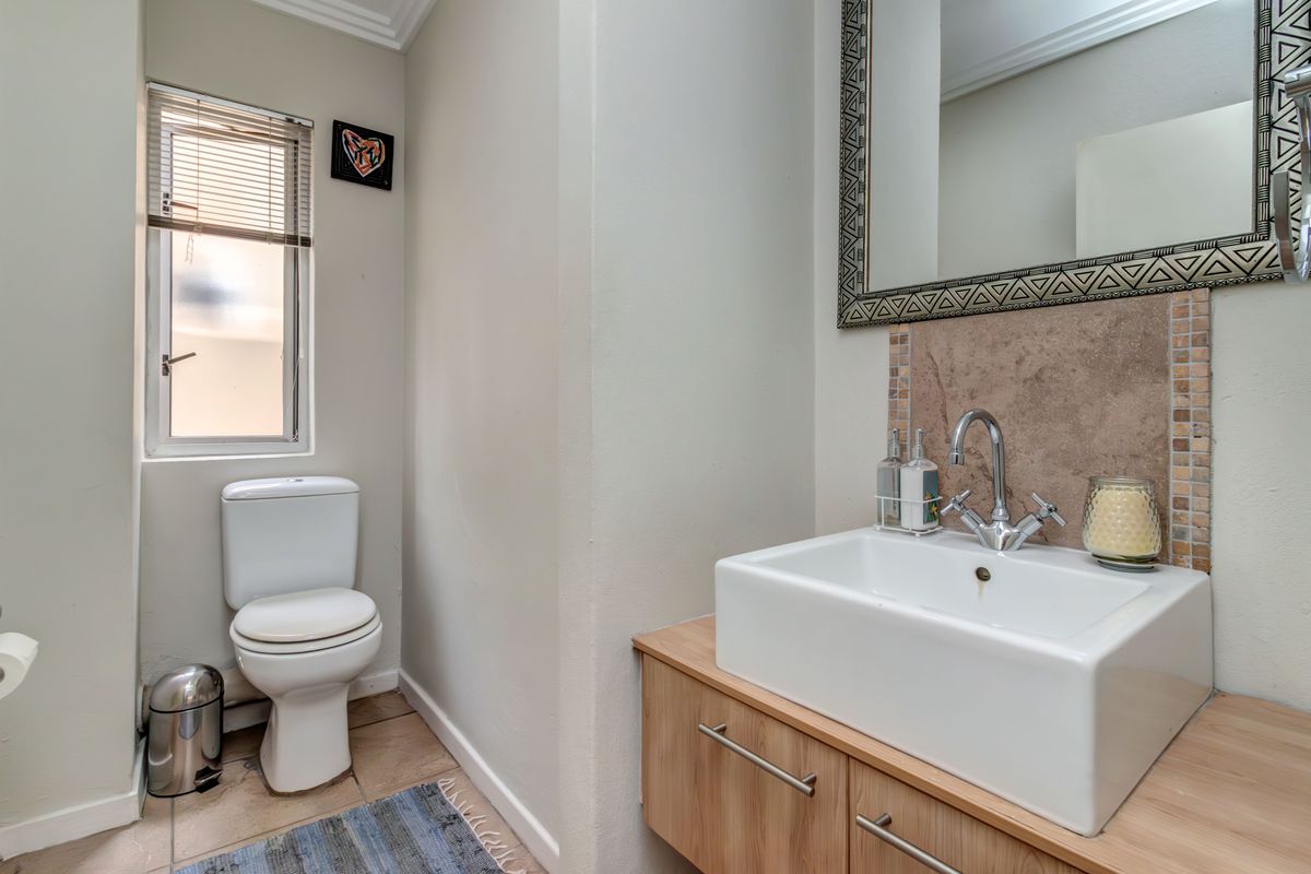 A well-maintained bathroom featuring a modern vessel sink on a wooden vanity, a tiled backsplash, and a framed mirror.