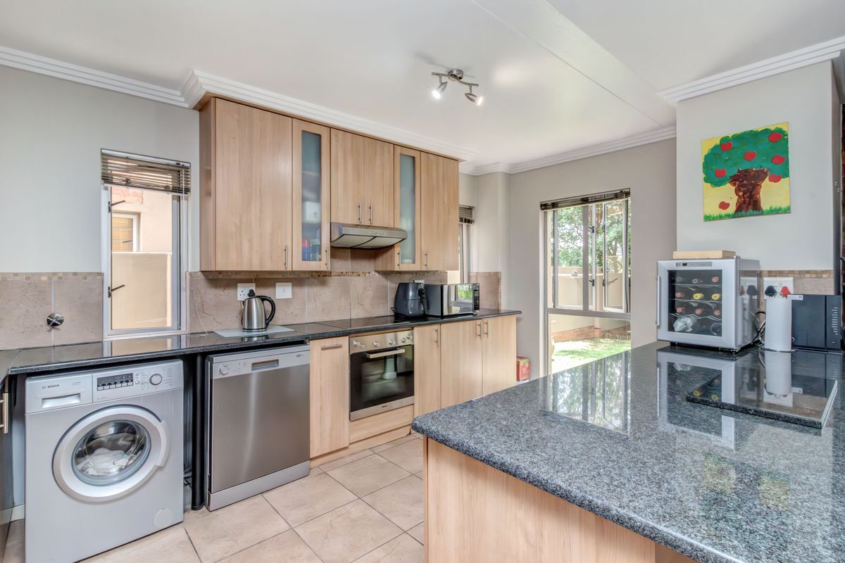 A functional kitchen featuring light wood cabinetry, granite countertops, a built-in oven, and tiled flooring with direct access to the exterior.