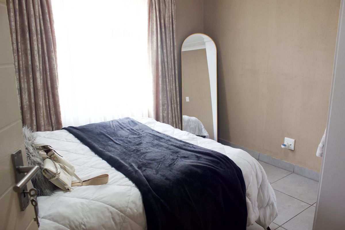 A bedroom featuring tiled flooring and neutral wall tones, providing a functional space with natural light from the window.