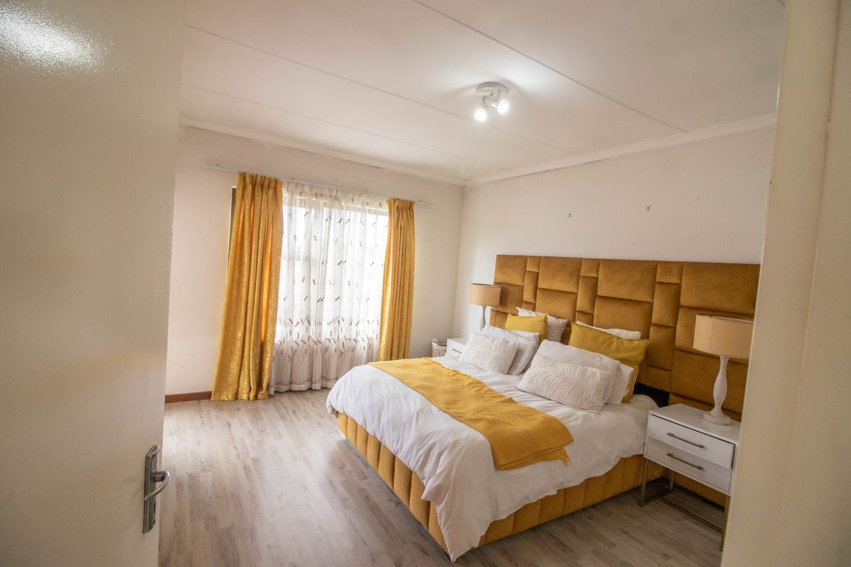 A well-lit bedroom featuring light-toned laminate flooring and a neutral color palette, providing a comfortable and functional sleeping space.