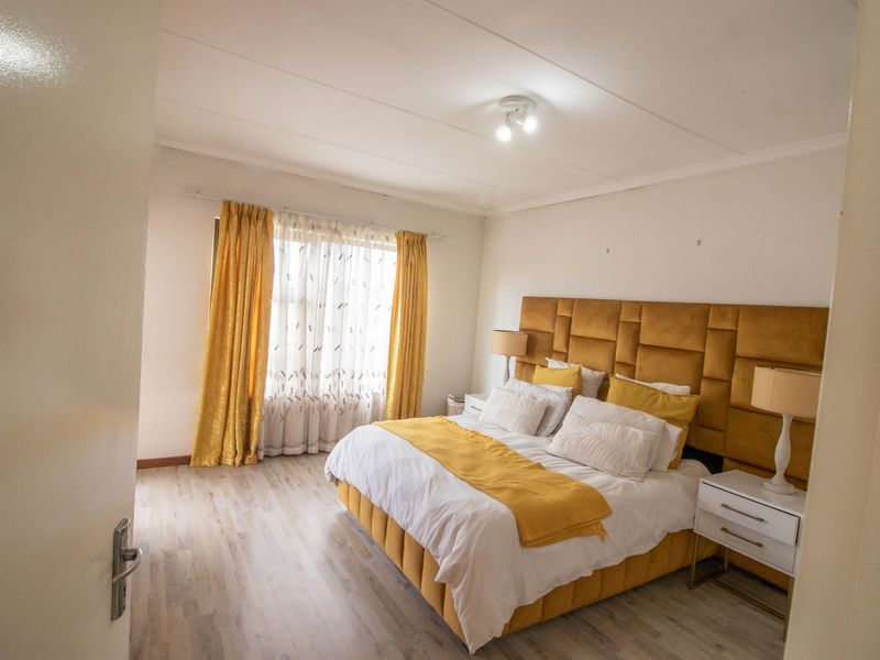 A well-lit bedroom featuring light-toned laminate flooring and a neutral color palette, providing a comfortable and functional sleeping space.