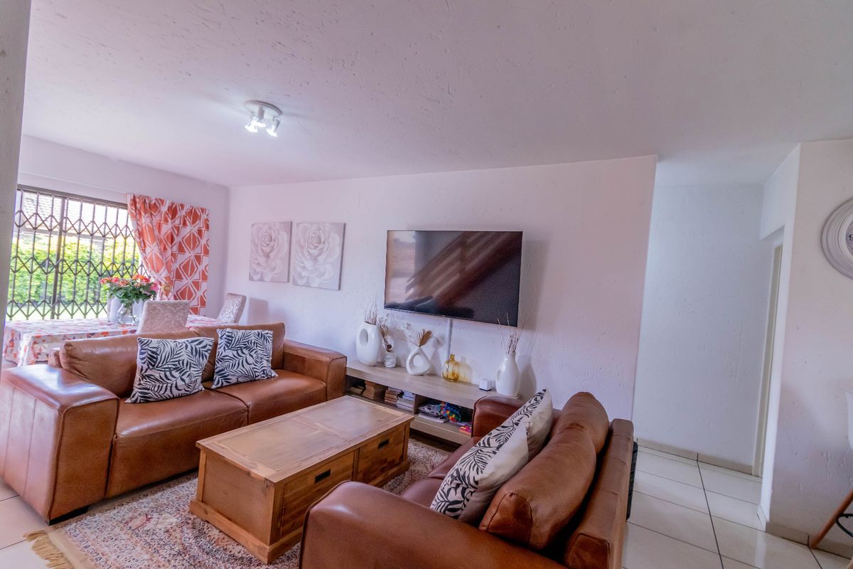 A comfortable living room featuring tiled flooring and a security gate on the window, providing a functional and well-lit space.