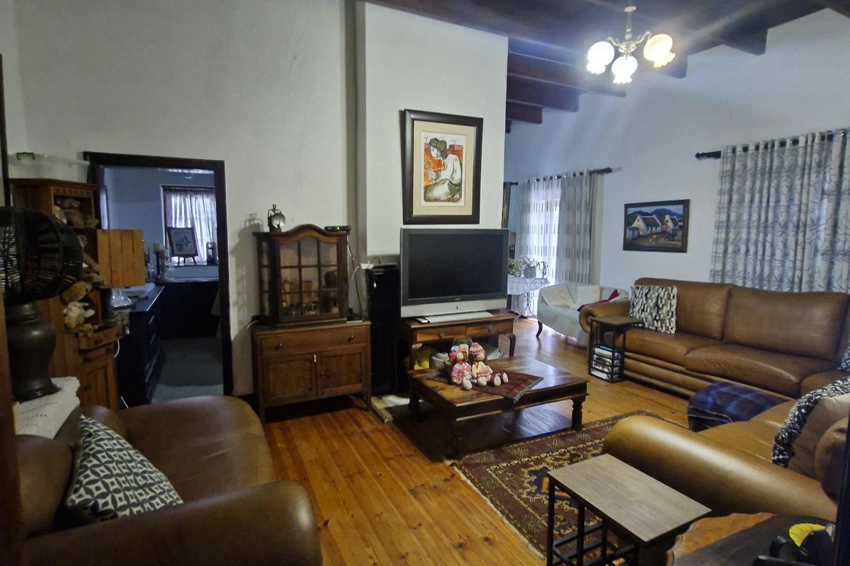 Spacious living room featuring exposed timber beam ceilings, warm timber flooring, and a central fireplace chimney breast.