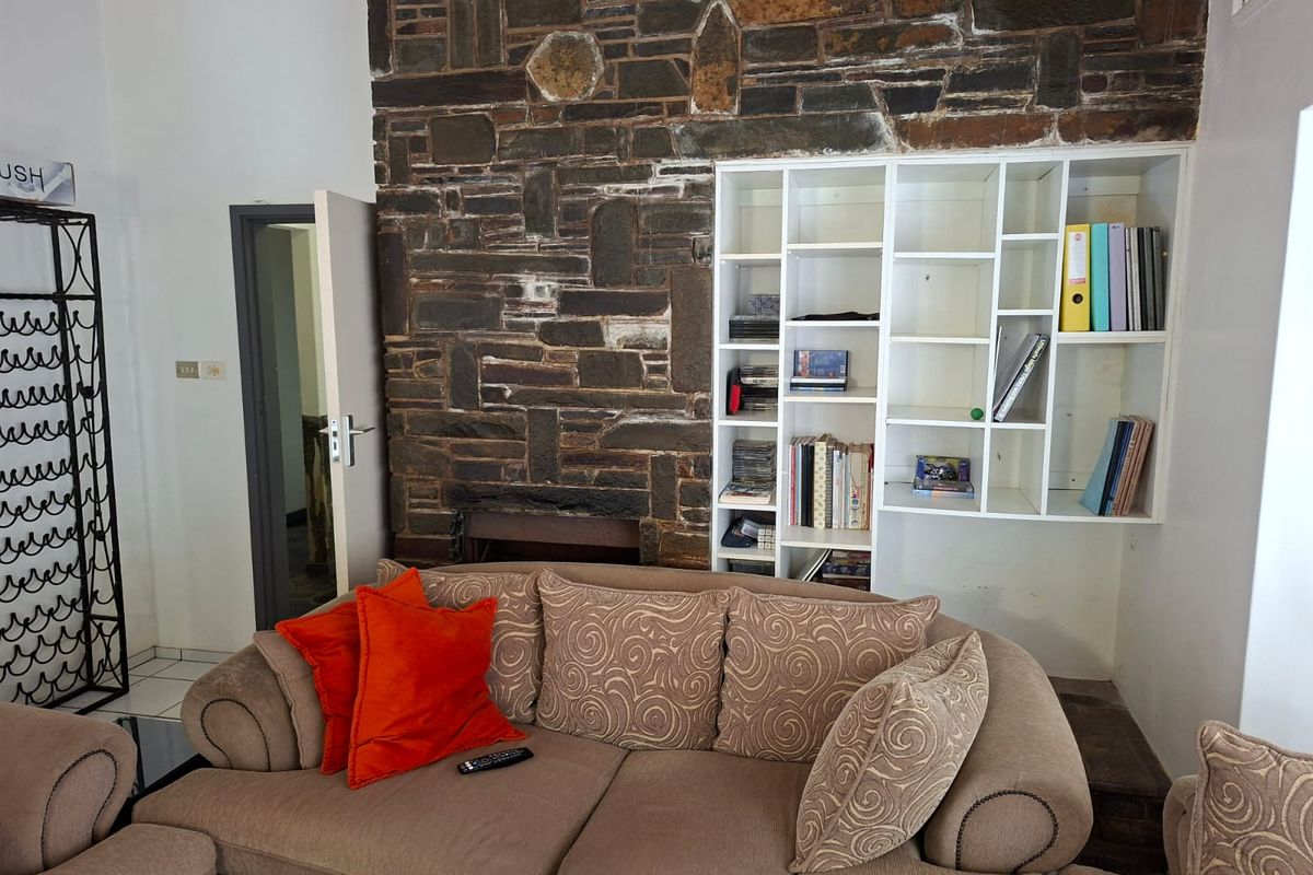 Living room featuring a prominent natural stone feature wall with an integrated fireplace and built-in shelving unit.
