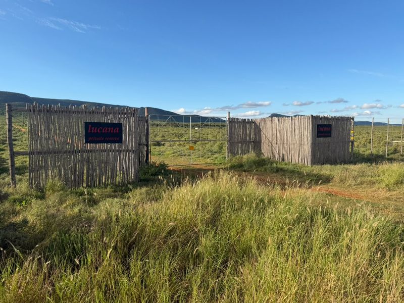 The main entrance gate to Lucana Private Reserve, featuring rustic timber pole fencing and a metal gate set against a natural landscape.