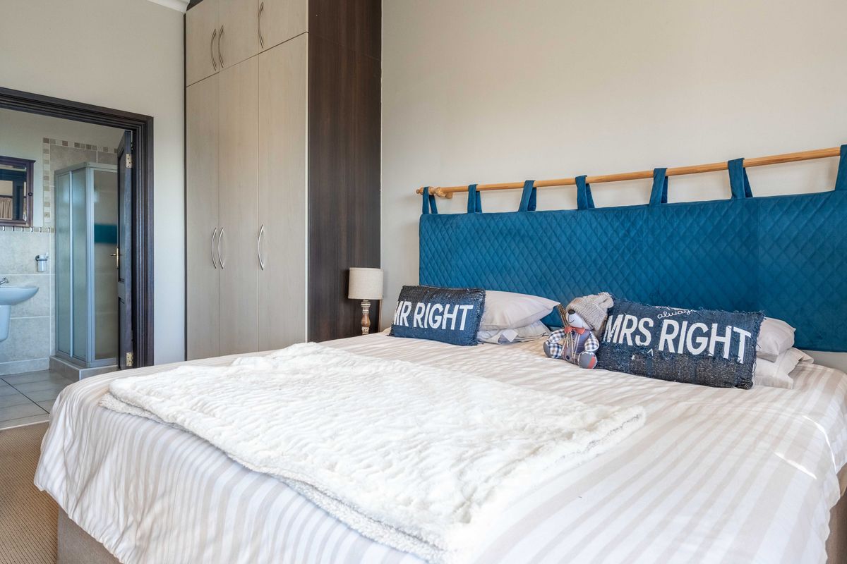 A well-maintained bedroom featuring built-in cupboards and direct access to an en-suite bathroom.