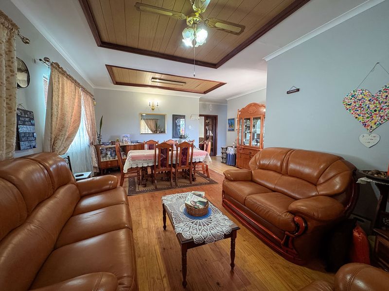 Open-plan living and dining area featuring hardwood flooring, timber-paneled ceilings with a central fan, and neutral wall finishes.