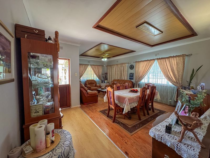 Spacious open-plan living and dining area featuring timber flooring and decorative timber ceiling panels.
