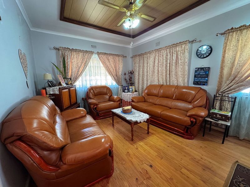 A living room featuring timber flooring and a timber-paneled ceiling with a central ceiling fan.