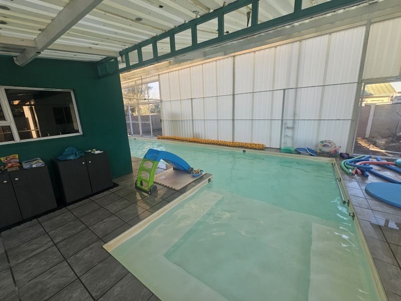 An indoor swimming pool area featuring tiled flooring and a translucent roof structure, providing a functional space for year-round swimming.