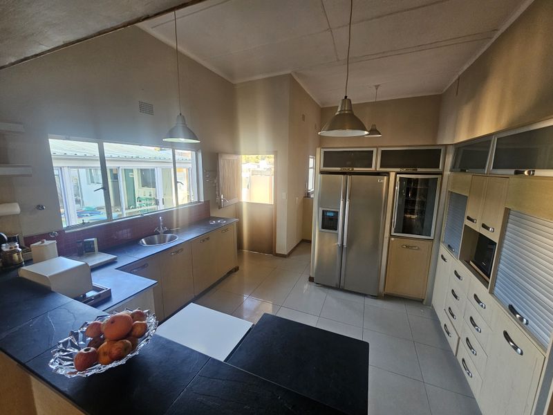 Spacious kitchen featuring extensive built-in cabinetry, stone countertops, tiled backsplash, and integrated appliances, offering a functional layout with ample storage and natural light.