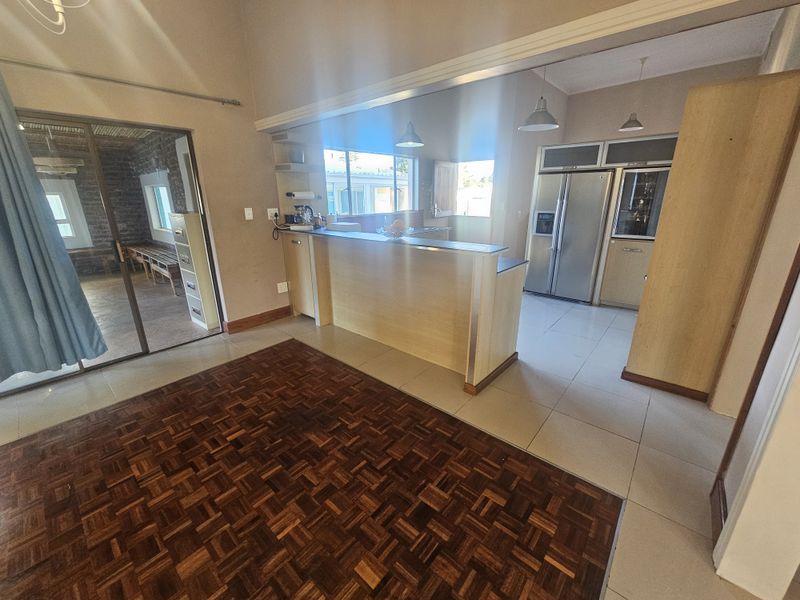 Open-plan living area featuring a combination of parquet and tiled flooring, a central kitchen island, and seamless flow to an adjacent room.