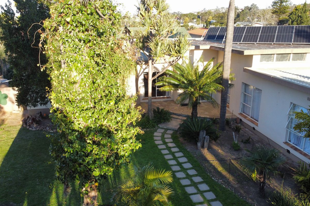 Aerial view of the property featuring a landscaped garden, paved walkway, and solar panels installed on the roof.