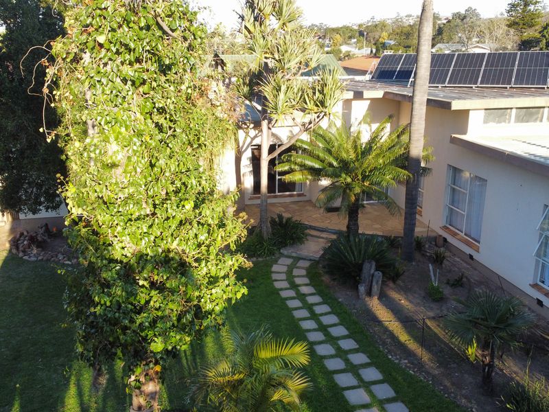 Aerial view of the property featuring a landscaped garden, paved walkway, and solar panels installed on the roof.