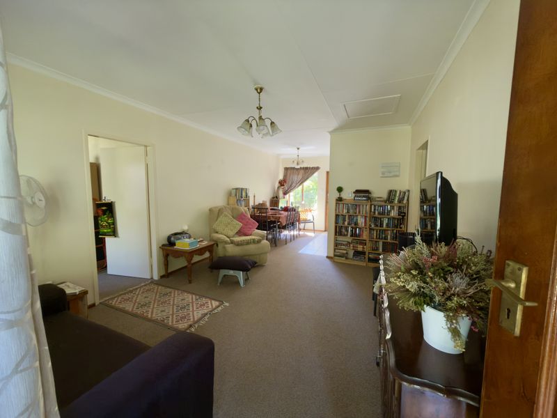 An open-plan living and dining area featuring neutral wall finishes, carpeted flooring, and access to adjacent rooms.