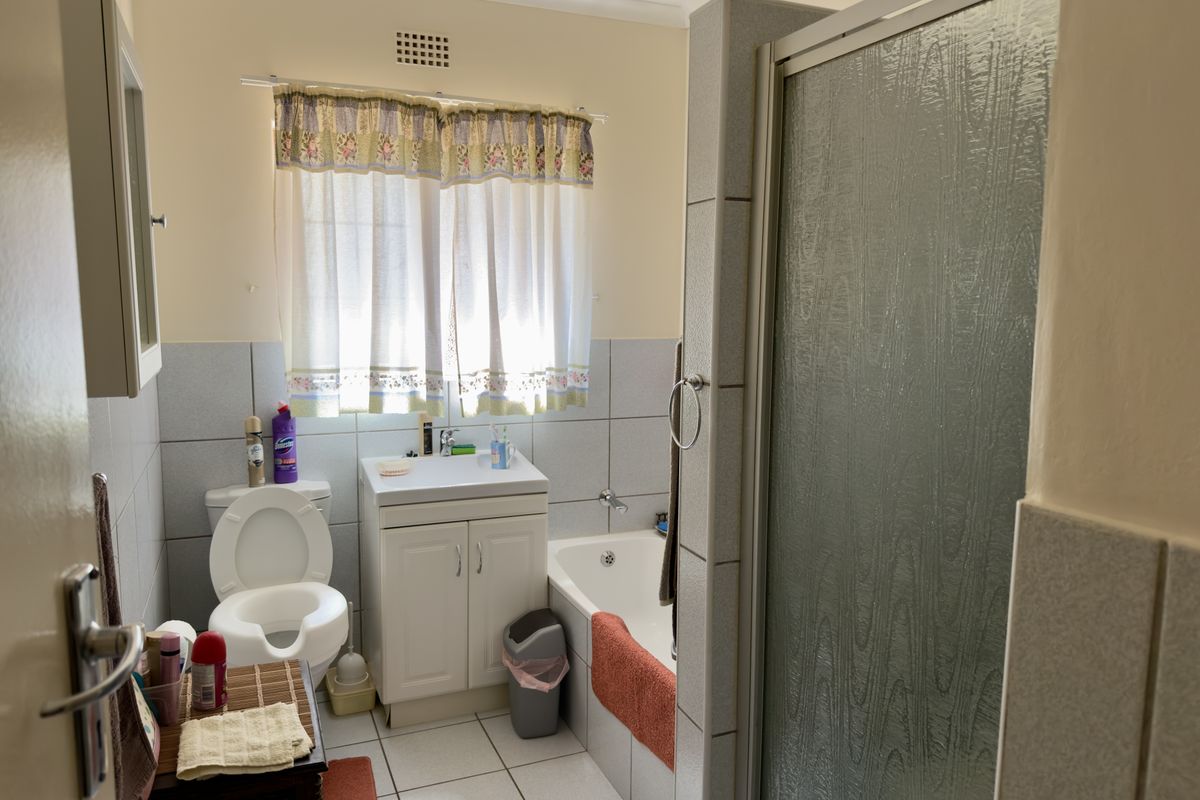 A functional bathroom featuring a vanity unit, bathtub, and separate shower enclosure with neutral wall and floor tiling.