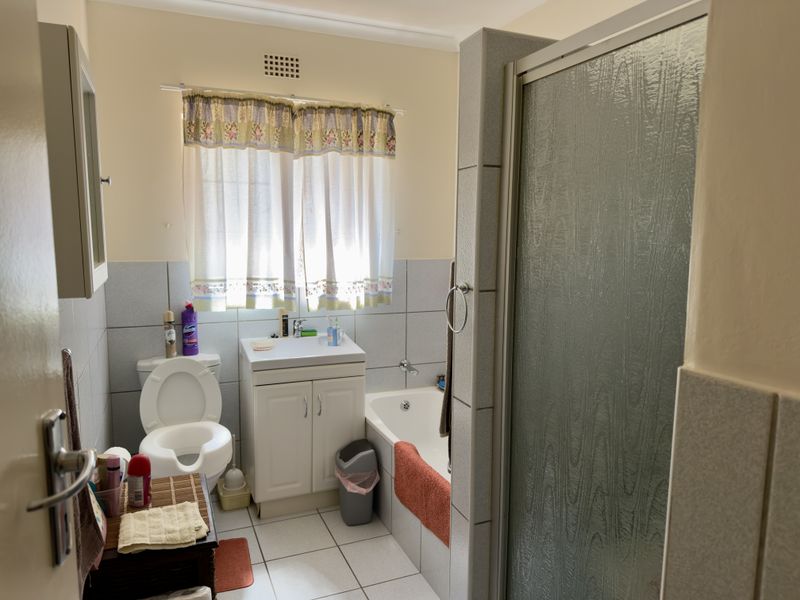 A functional bathroom featuring a vanity unit, bathtub, and separate shower enclosure with neutral wall and floor tiling.